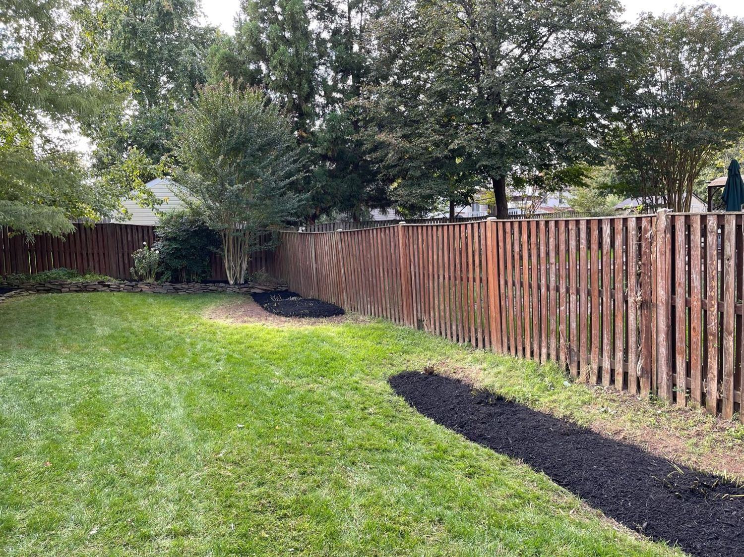 Mulched planting bed along a fence line
