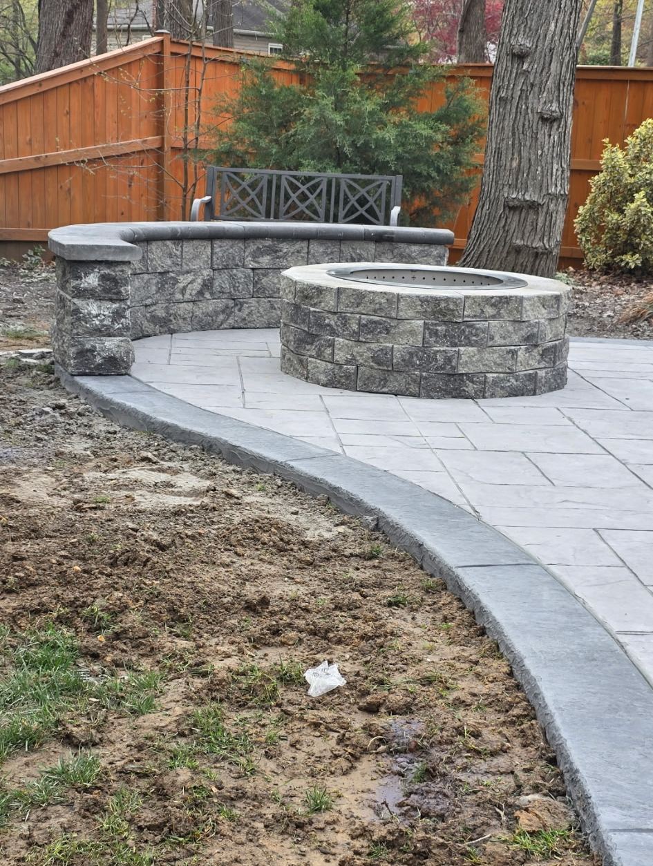 Block fire pit and curved seat wall on a stamped patio