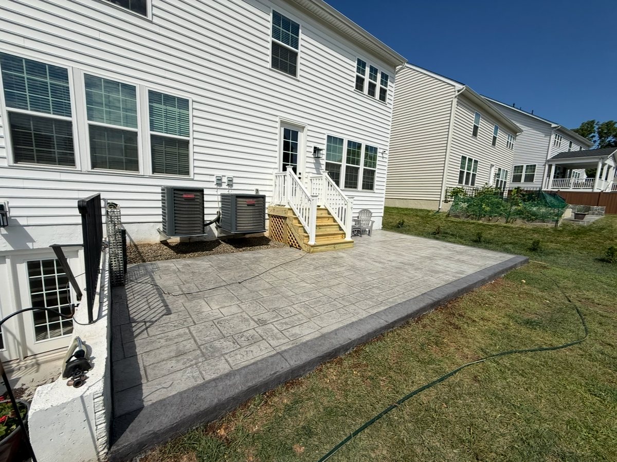 Wide stamped concrete patio behind a home