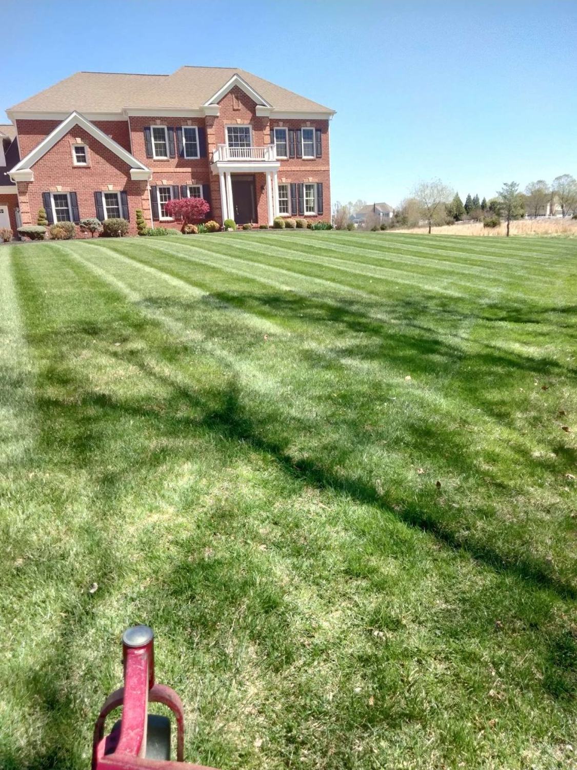 Striped lawn maintenance on a brick colonial in Loudoun County